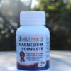 A bottle of Cabot Health Magnesium Complete tablets, labeled as "The Great Relaxer." The label highlights benefits such as relieving headache symptoms, reducing stress, improving sleep, and relieving muscle cramps. The bottle contains 100 tablets.
